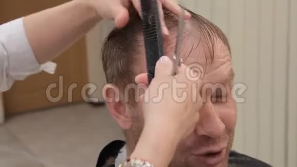 一位年轻有趣的男子在理发店理发时正积极地告诉发型大师而视频的预览图