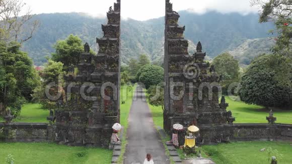游客妇女在贝都古尔传统巴厘岛印度教门坎迪本塔穿过巴厘岛传统大门的后景视频的预览图