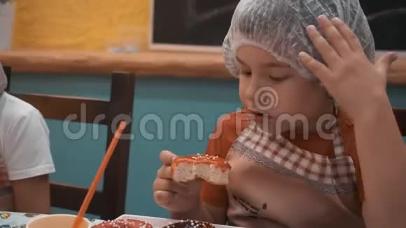肖像可爱的男孩咬和咀嚼甜甜甜圈与焦糖釉在面包店把做饭的男孩关起来吃上釉面甜甜圈视频的预览图