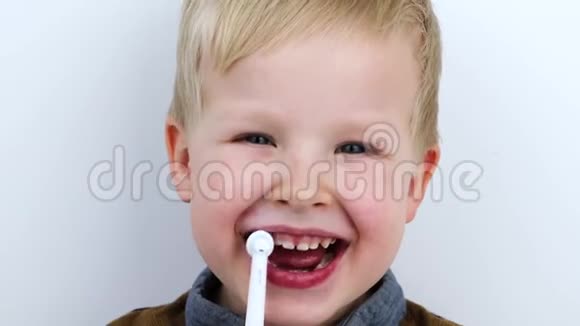 四岁的孩子用电刷刷牙白色背景的男孩笑着拿着牙刷这就是视频的预览图