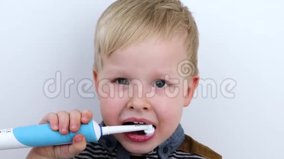 四岁的孩子用电刷刷牙白色背景的男孩笑着拿着牙刷这就是视频的预览图