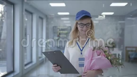 年轻的微笑女孩戴着眼镜和帽子在送货服务中工作女员工花束给视频的预览图