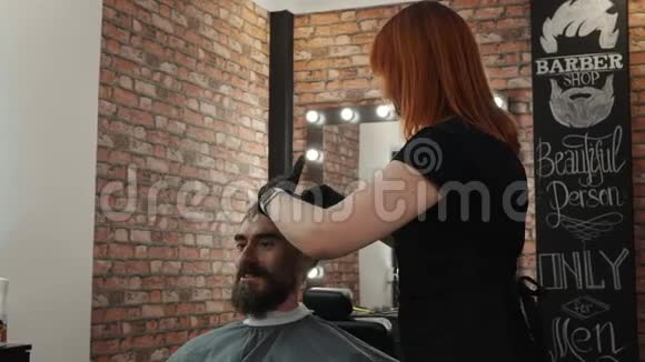 快乐的留胡子的男人在理发店理发时和理发师说话理发师为巴伯的嬉皮士理发视频的预览图