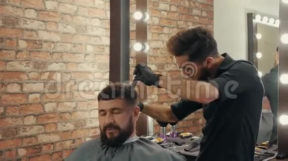 肖像帅哥在理发店接受时尚发型理发师在男性沙龙理发美容师使用视频的预览图
