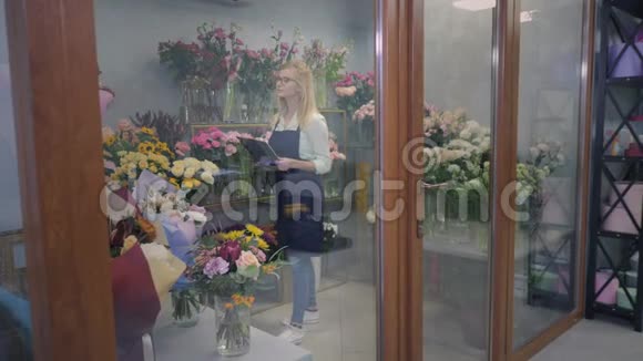 年轻的女花店在温室里工作检查开花情况为送花制作花束视频的预览图