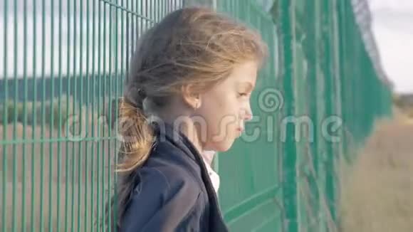 贫穷的小女孩倚在移民营地的网栅边概念抑郁状态未成年儿童孤独和被遗弃视频的预览图