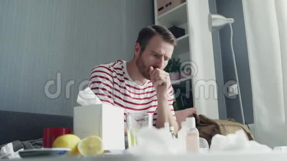 一个戴着围巾的年轻人因为感冒和喉咙痛而扼住脖子咳嗽在他的客厅里视频的预览图
