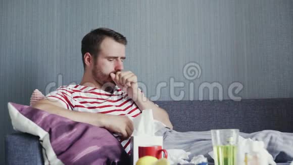 一个男人咳嗽得很厉害一边坐在客厅的沙发上一边吹鼻子视频的预览图
