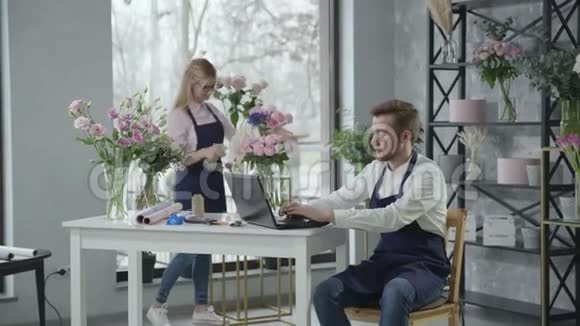小生意年轻的花店团队在花店工作并在网上订购鲜花事业成功视频的预览图
