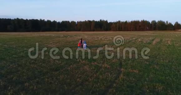 两位母亲带着女儿在日落时在田野里散步和玩耍空中观景视频的预览图
