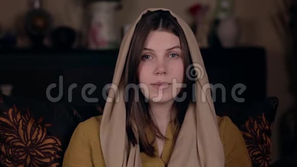 一位年轻漂亮的基督教妇女头上戴着围巾外表是白人坐在椅子上在网上祈祷视频的预览图