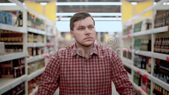商店里的一个男人正在超市里看商品一个男人推销购物车挑选商品视频的预览图