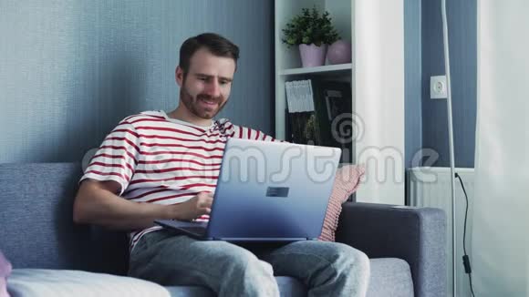 快乐微笑的年轻人在家看电脑和工作视频的预览图