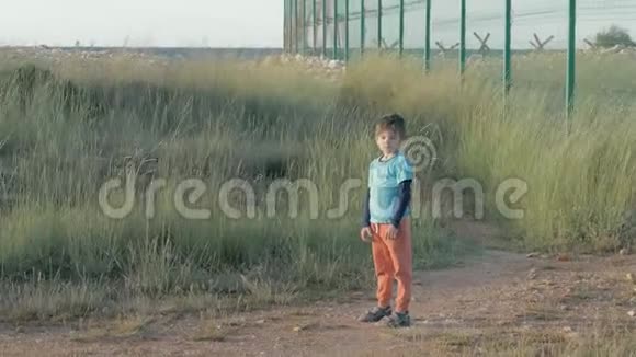 战争和武装冲突的孩子小男孩破旧的衣服站在边境的网栅附近孤独儿童封闭区视频的预览图