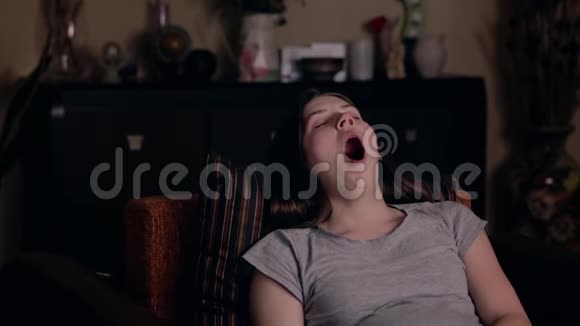 一个年轻的欧洲女孩很累在家里的扶手椅上睡着了疲劳的概念有趣搞笑视频的预览图