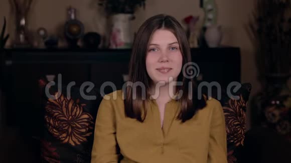 一个年轻的白人女孩坐在椅子上笑着对着镜头尴尬欢快的表演理念视频的预览图