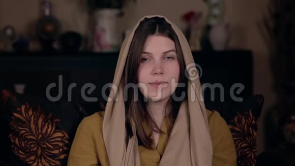 一位年轻漂亮的基督教妇女头上戴着头巾外表是高加索人坐在扶手椅上记录着一张视频的预览图