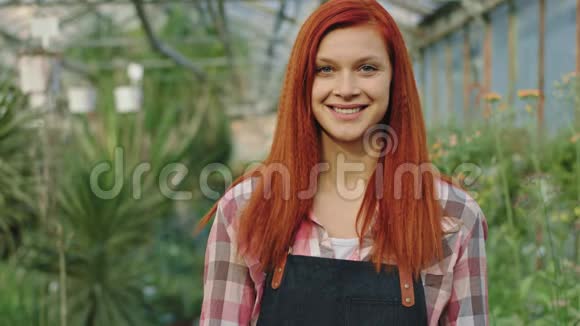红发花房里漂亮的园丁正对着镜头微笑露出一个大的样子视频的预览图