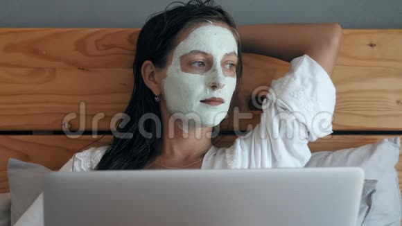 带着口罩的女人躺在床上手提电脑视频的预览图