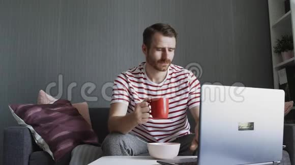 大胡子微笑的男人喝茶滚动电脑视频的预览图