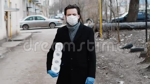 佩戴医用口罩及手套的男子用手纸卷预防冠状病毒流行视频的预览图