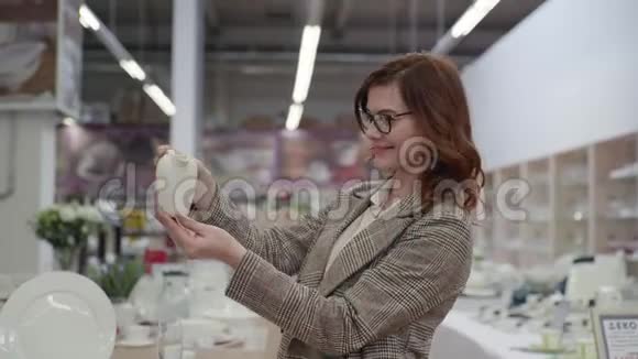 年轻快乐的女购物者为她的公寓选择茶具和盘子漂亮的女人戴着眼镜视频的预览图