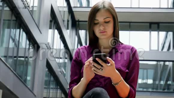 自信的女商人在办公楼的背景下使用手机上网视频的预览图