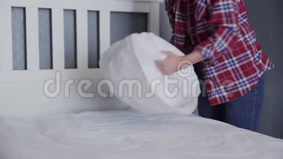 女人在卧室里打扫她的床漂亮的女人摆好床整理她的枕头和垫子视频的预览图