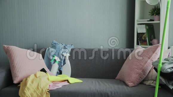 筋疲力尽的戴手套的女人坐在沙发上在打扫房子后放松视频的预览图