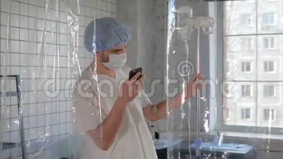一名戴着医用口罩的年轻男子在医院使用电话进行隔离视频的预览图