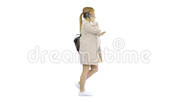 孕妇背着背包走着在白色背景上打电话视频的预览图
