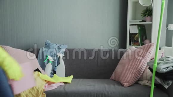 筋疲力尽的戴手套的女人坐在沙发上在打扫房子后放松视频的预览图
