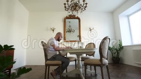 呆在家里隔离检疫期间一名男子在家里用电脑工作现代室内视频的预览图