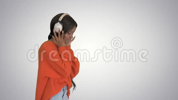 快乐的非洲女人戴着无线耳机在梯度背景上听音乐视频的预览图
