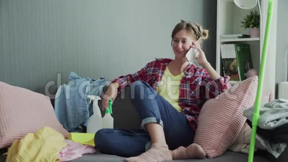漂亮的年轻女子在打扫完房间并通了电话后正在沙发上休息视频的预览图
