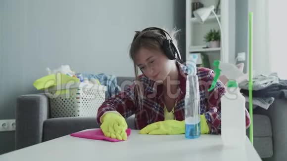 一个疲惫的女人用粉色的海绵努力清除桌子上的灰尘视频的预览图