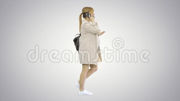孕妇背着背包行走在梯度背景下在电话上交谈视频的预览图