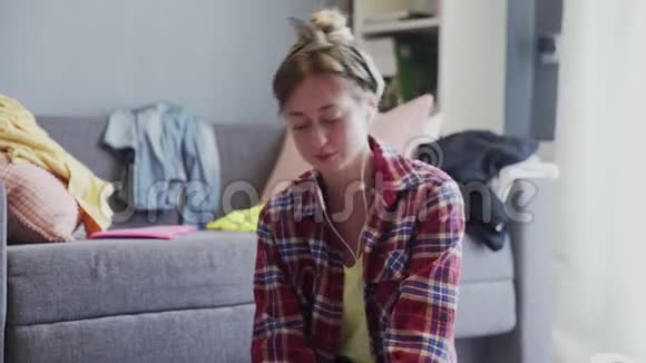 一个戴着耳机的女人正在打扫客厅的地板视频的预览图