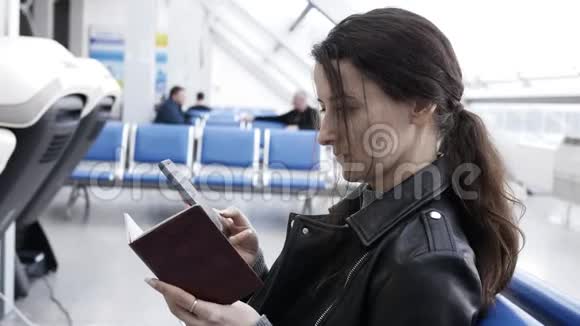 年轻女子在机场通过电话购买机票她输入护照资料购买机票视频的预览图