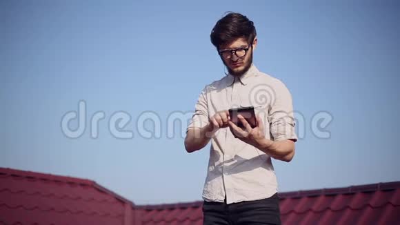 房子屋顶上年轻快乐的时髦女郎的肖像带着智能手机和耳机听音乐戴着圆形太阳镜视频的预览图