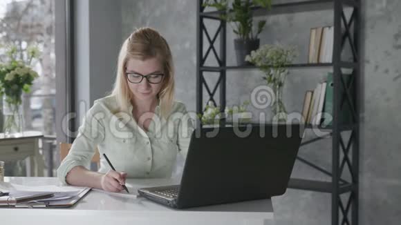 商务在线快乐迷人的女孩自由职业者在办公室的笔记本电脑上工作鲜花盛开视频的预览图