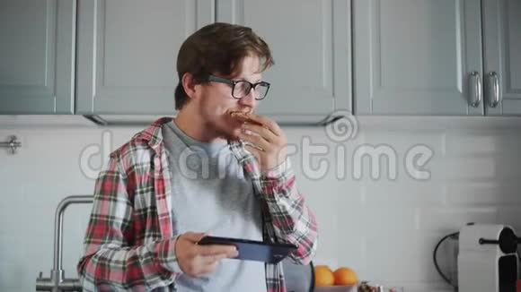 带着药片的年轻人吃巧克力糊的吐司男人在平板电脑上看有趣的视频笑视频的预览图