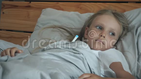 一个带体温计的小女孩躺在床上视频的预览图
