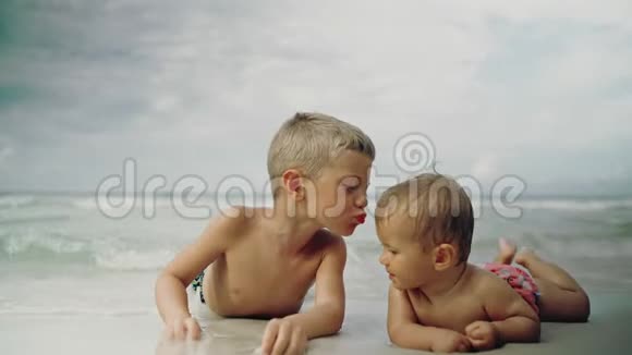 小可爱的女婴和她的弟弟躺在海滩上巴拿马城市海滩视频的预览图