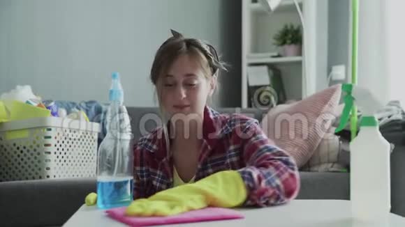 年轻女子用粉色海绵去除桌子上的灰尘视频的预览图