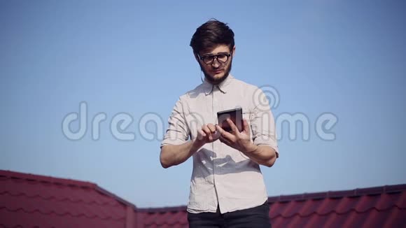 房子屋顶上年轻快乐的时髦女郎的肖像带着智能手机和耳机听音乐戴着圆形太阳镜视频的预览图