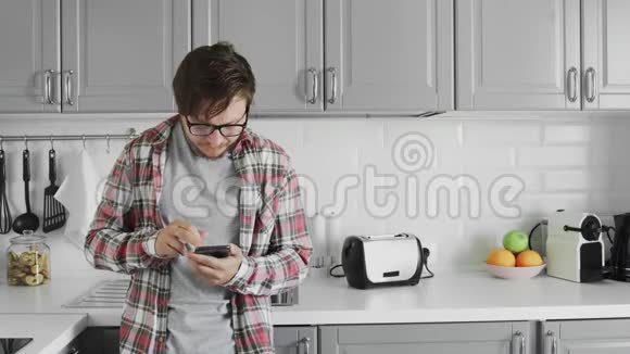有魅力的年轻人在家里的厨房里用电话视频的预览图