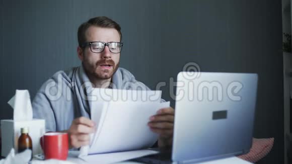 生病期间在家工作的年轻自由职业者带手提电脑和文件在家工作的病人视频的预览图