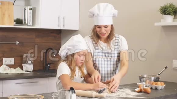 女人和可爱的女儿在厨房做饭为生日聚会做面团视频的预览图