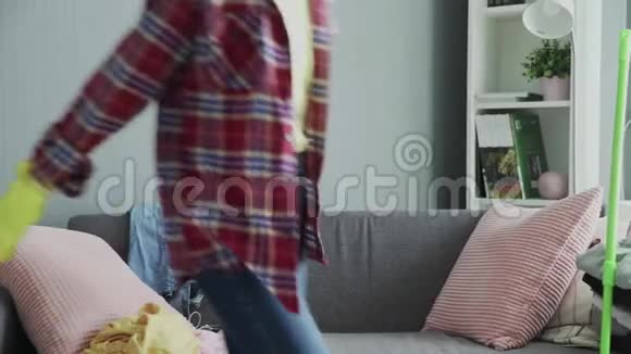 戴着手套的微笑女人坐在沙发上在打扫房间后放松视频的预览图